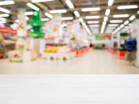 White wooden board empty table in front of blurred background. Perspective white wood over blur in supermarket - can be used for display or montage your products. Mockup for display of product.