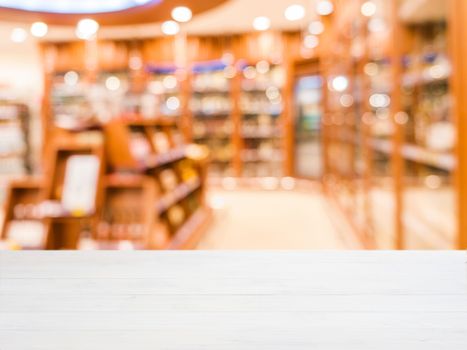 White wooden board empty table in front of blurred background. Perspective white wood over blur in department of alcoholic drinks in supermarket - Mockup for display or montage your products