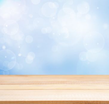 Wooden board empty table in abstract blue background with bokeh. Perspective light wood board over blurred blue background - mockup for display of product