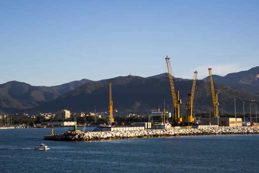 Panoramic view of a commercial port in a sunny morning with mountains in the background