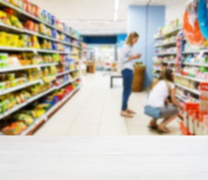 White wooden board empty table in front of blurred background. Perspective white wood over blur in supermarket - can be used for display or montage your products. Mockup for display of product.