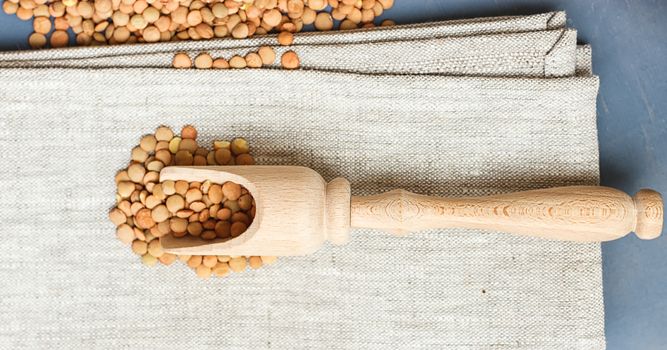 raw lentils on a wooden spoon on a linen cloth