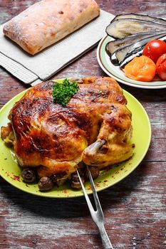 Whole roasted chicken with baked vegetables on wooden background