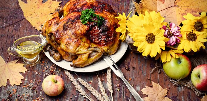 Whole roasted chicken with baked vegetables on wooden background