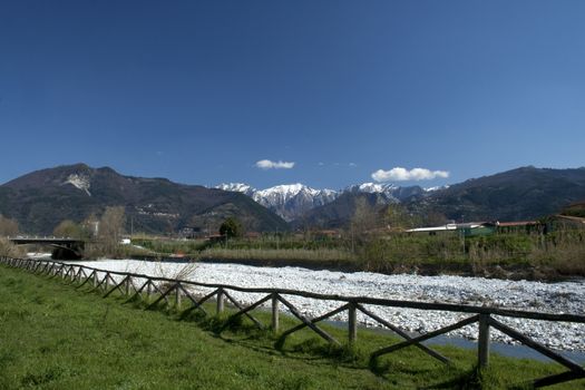 view of a portion of the fence and the river with a backdrop of the Apuan Alps