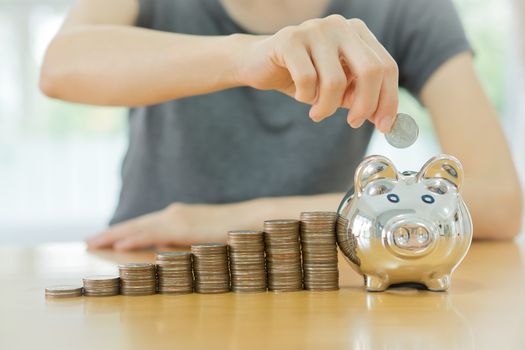saving money-young woman putting a coin into a money-box-close up