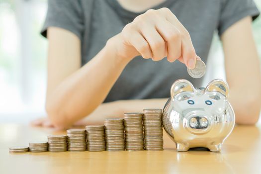 saving money-young woman putting a coin into a money-box-close up