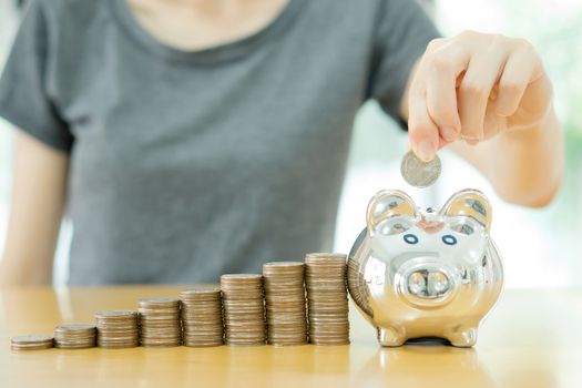 saving money-young woman putting a coin into a money-box-close up