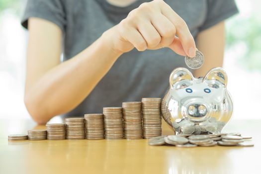saving money-young woman putting a coin into a money-box-close up