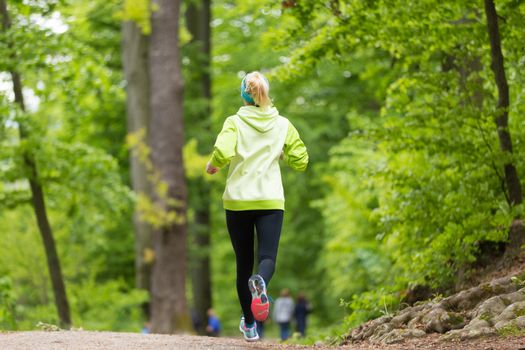 Sporty young female runner in forest.  Running woman. Female runner during outdoor workout in nature. Fitness model outdoors. Weight Loss. Healthy lifestyle. 