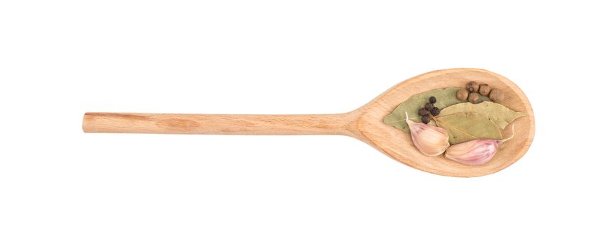 Garlic in a wooden spoon with bay leaf herb and black peppercorns isolated over white background.