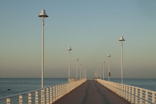 Sequence of lamps alternating with a sense of infinity of a marine pier of Marina of Massa