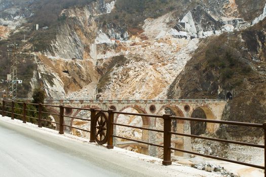 Road of marble with parapet with symbol of rotation in the background with a marble quarry and the bridge of Vara