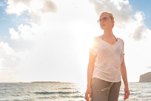 Relaxed woman enjoying sun, freedom and life an a beautiful sandy beach. Young lady feeling free, relaxed and happy. Vacations, freedom, happiness, enjoyment and well being.