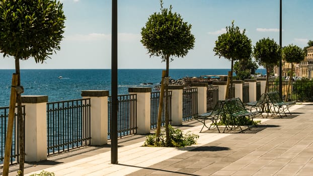 Bench and little trees at the sicilian sea, Italy.