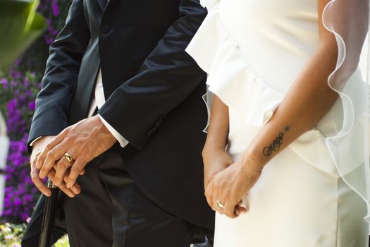 View a detail of the hands of the bride and groom with rings