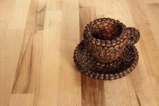 Close up view of a cup covered with coffee beans on a wooden surface