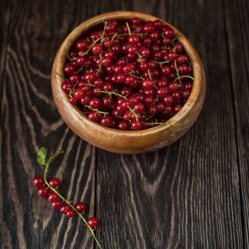 Fresh red currants in plate on wooden table