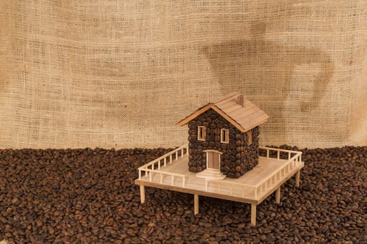 House made of coffee on sea of coffee and background screening shadow of a coffee machine