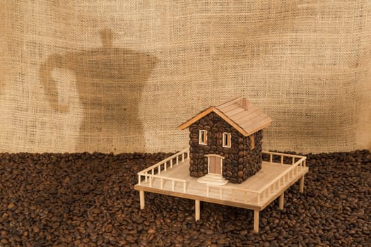 House made of coffee on sea of coffee and background screening shadow of a coffee machine