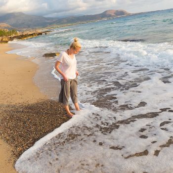 Woman walking on sand beach at golden hour. Seashore sunset walk.