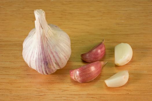 Garlic cloves on a brown breadboard