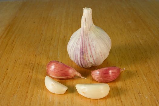 Garlic cloves on a brown breadboard
