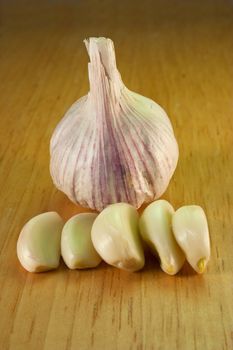 Garlic and 5 cloves on a brown breadboard