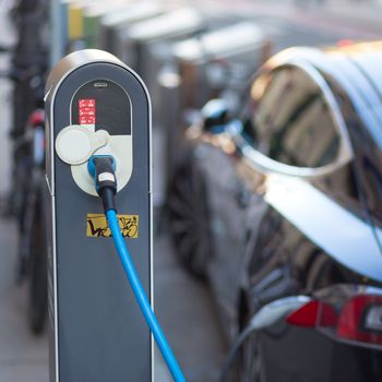 Power supply for electric car charging.  Electric car charging station. Close up of the power supply plugged into an electric car being charged.