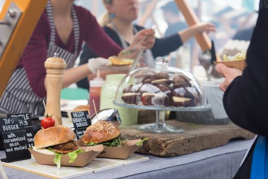Tofu vegetarian burgers being served on food stall on open kitchen international food festival event of street food.