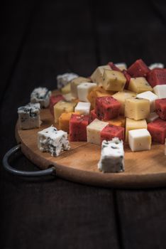 many kinds of cheeses on wooden end of a tree