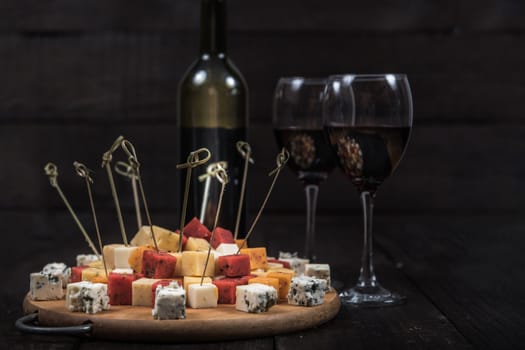 many kinds of cheeses on wooden end of a tree with reed wine