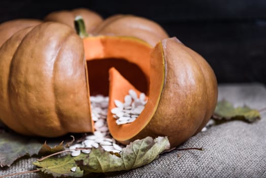 pumpkin lying on a wooden table with viburnum and seeds