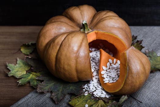 pumpkin lying on a wooden table with viburnum and seeds