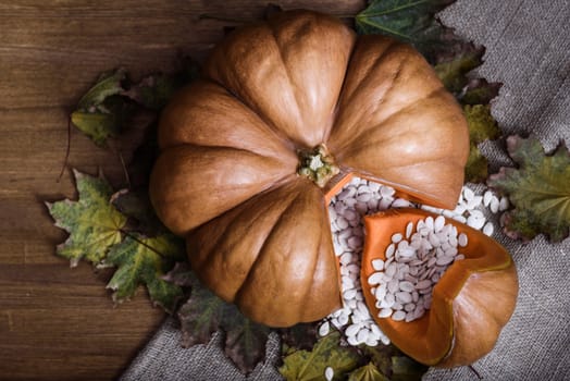 pumpkin lying on a wooden table with viburnum and seeds