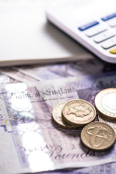 British pounds coins and notes on table with calculator