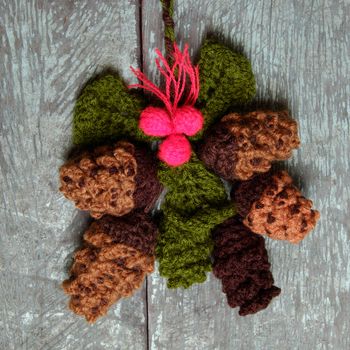 Nice handmade ornament for winter holiday, group of knitted pinecone, holly leaf, berries knit from yarn, message Merry Christmas on tag, nice Xmas background