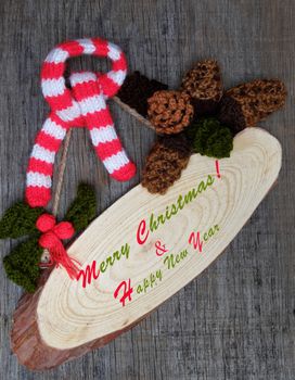 Nice handmade ornament for winter holiday, group of knitted pinecone, holly leaf, berries knit from yarn, message Merry Christmas on tag, nice Xmas background