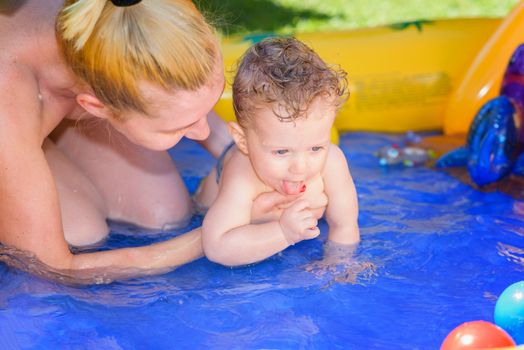 Mother and son play in a small paddling pool