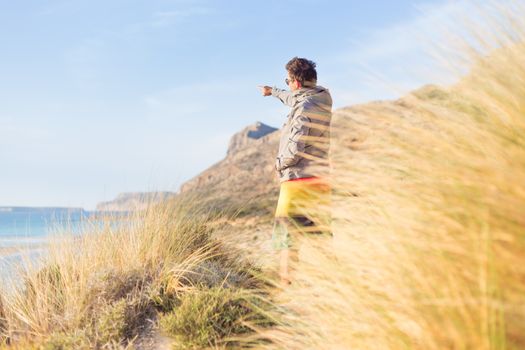 Sporty active man pointing hand on horizon, enjoying beauty of nature, freedom and life at beautiful landscape. Active lifestyle outdoors.