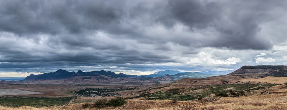 Running storm clouds on a background of mountains. Panorama
