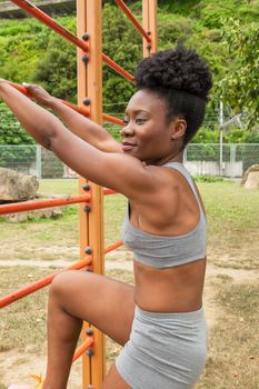 African young woman doing stretching exercises in urban structures for sports in a city park