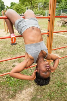 African young woman doing abdominal exercises in urban structures for sports in a city park