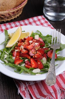 Salad of arugula and strawberries with crushed peanuts, almonds