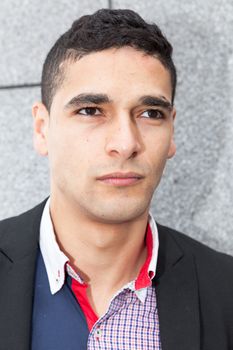 Young elegant arab man thinking next to a stone wall