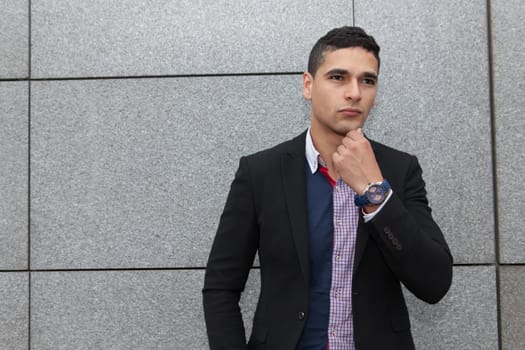 Young arab man posing  next to a stone wall