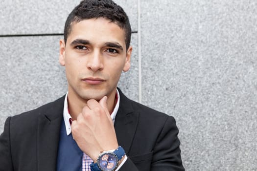 Young arab man posing  next to a stone wall