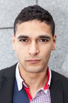 Young elegant arab man thinking next to a stone wall