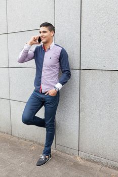 Young arab man talking on the phone next to a stone wall