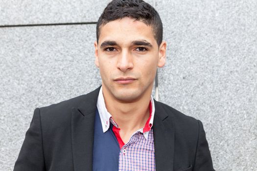 Young elegant arab man thinking next to a stone wall